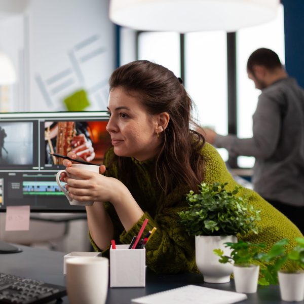 Young sound engineer working on video footage during post production talking with colleague. Content creator editing montage of film using modern software for processing sharing ideas with coworker